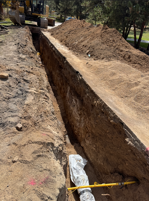 Photo of cut trench wtih pipe lying at the bottom of part of the trench