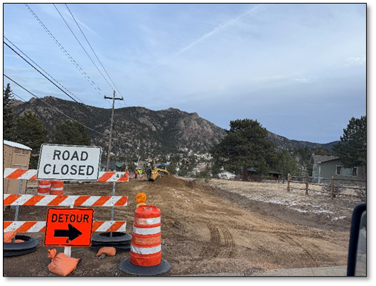 A picture of a road closed and detour sign along a road.