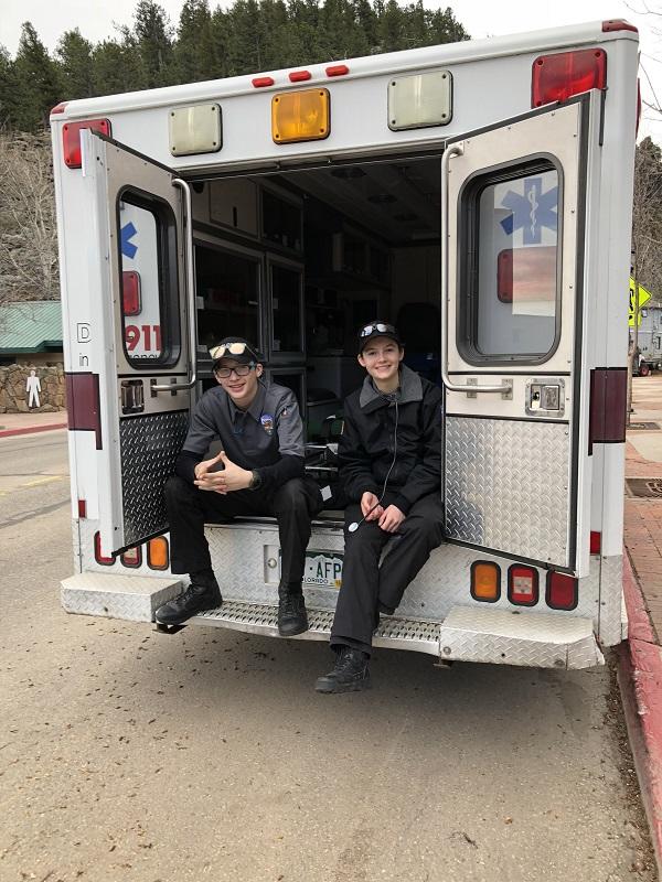 Two uniformed youth Explorers sitting on the open bay of an ambulance 