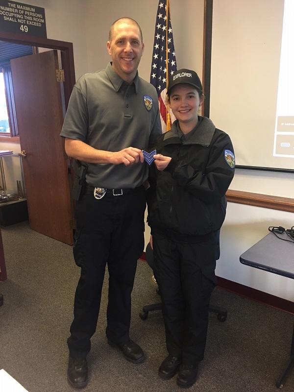 Former Explorer Advisor Officer Plassmeyer posing with youth participant who is receiving her chevron patch