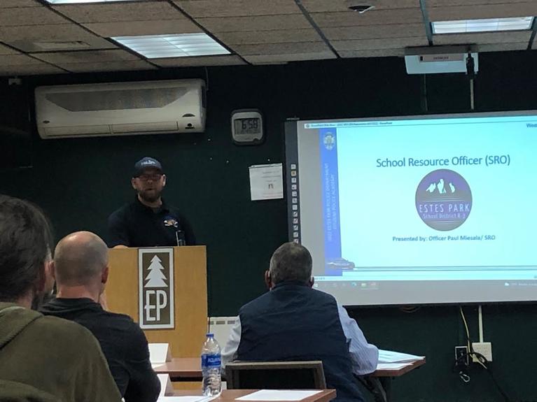 Estes Park School Resource Officer presenting at podium with screen